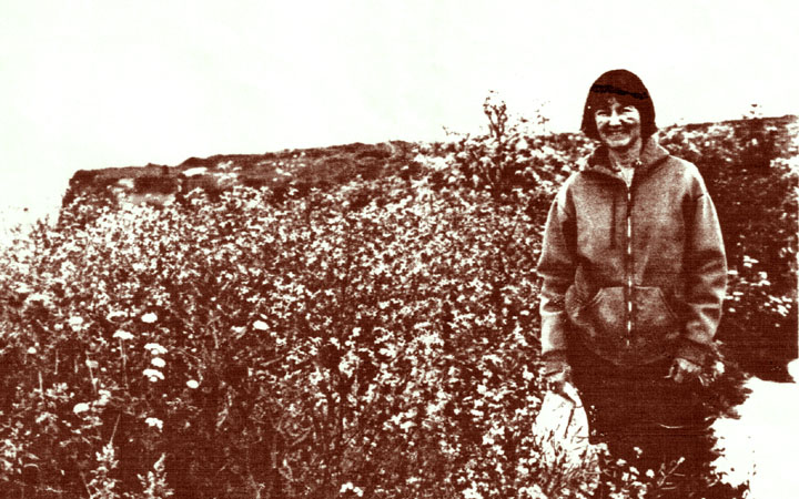 sepia photo of painter Marcia Pagels in wildflowers near cliff edge, Pebble Beach/Bean Hollow CA, 1997