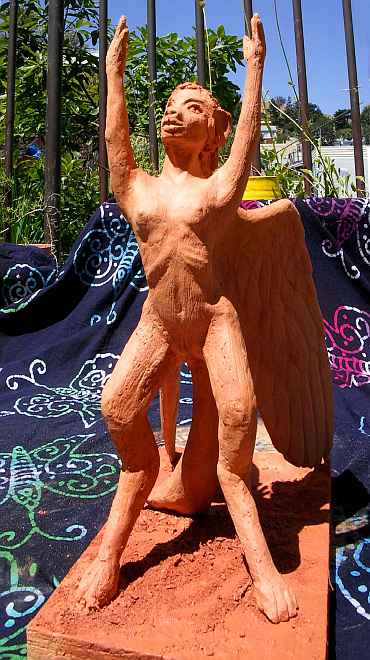A lebbird (a winged, bipedal feline woman) looking up and raising both arms ecstatically, wings half-spread. Unfired clay sculpture. Click to enlarge.