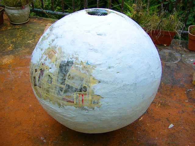 Photo of a big papier-mache egg, mostly white, some newspaper still showing.