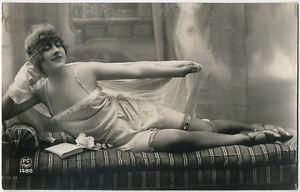 woman on couch in nightgown; old black and white postcard c.1920.
