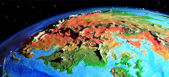 Low orbital photo of western continent 2 on Pegasia, an Earthlike moon. Green coast, inland desert, snowy ranges on horizon.