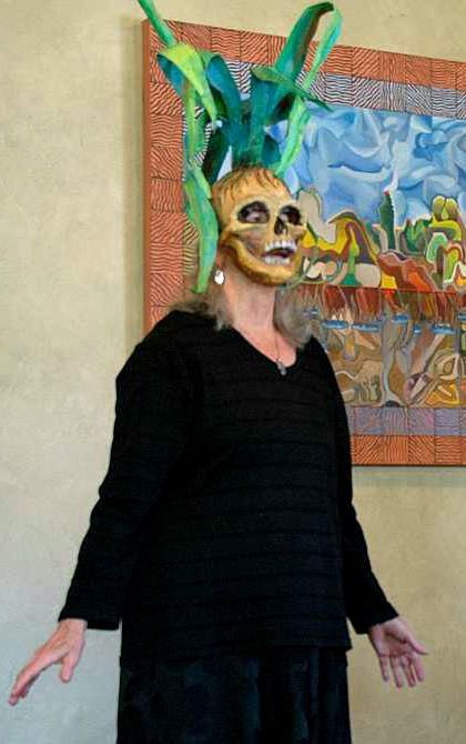 Photo of Jenny Badger Sultan in a skull mask from which corn stalks grow.