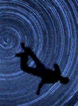 silhouette of a falling figure against a time exposure of the night sky--stars turned to circles